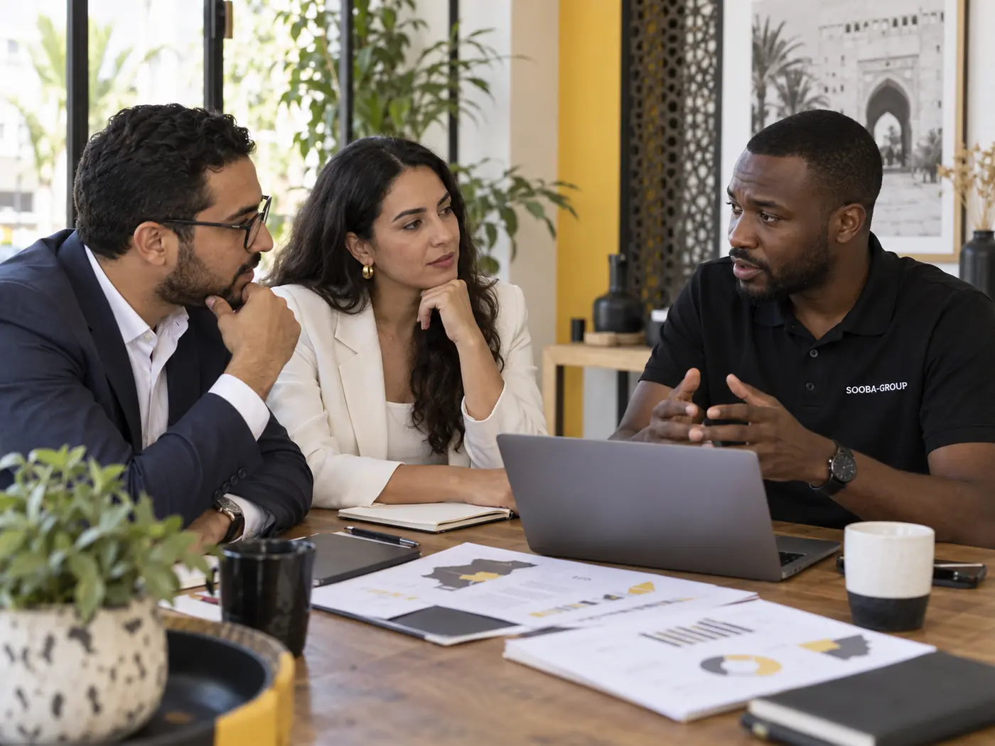 Une conseillère Sooba Group échange avec des porteurs de projet autour d'un ordinateur.